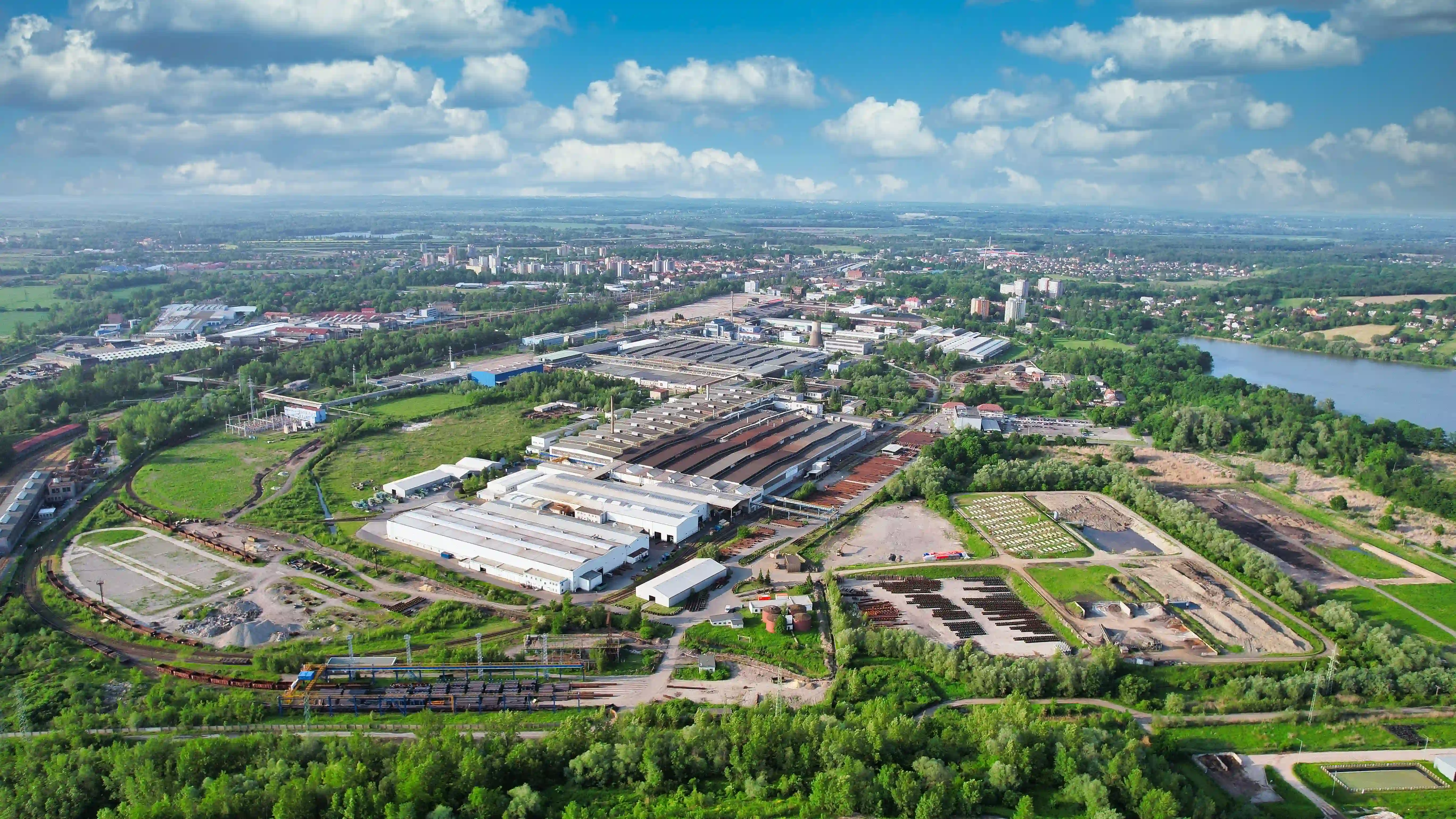 Luftaufnahme eines Industrieareals mit Produktionshallen an einem Fluss